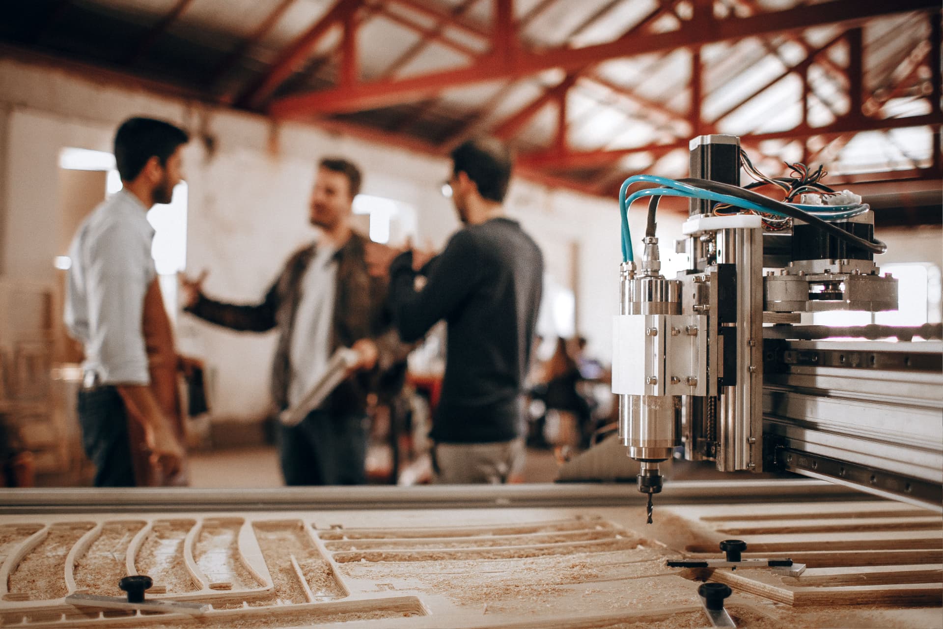 Three business owners reviewing a project together in a machine workshop